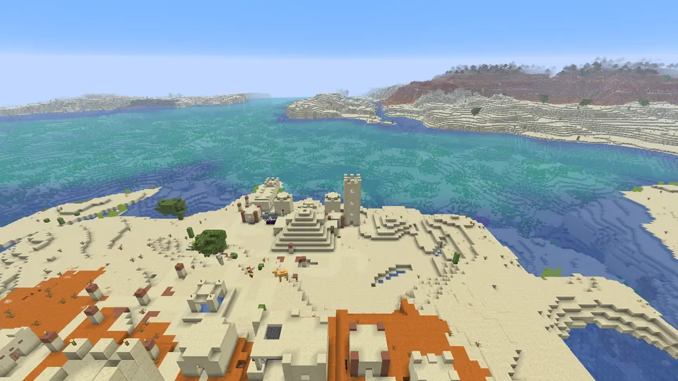 Sandstone desert temple on pale sand beside orange badlands and clear coastal water